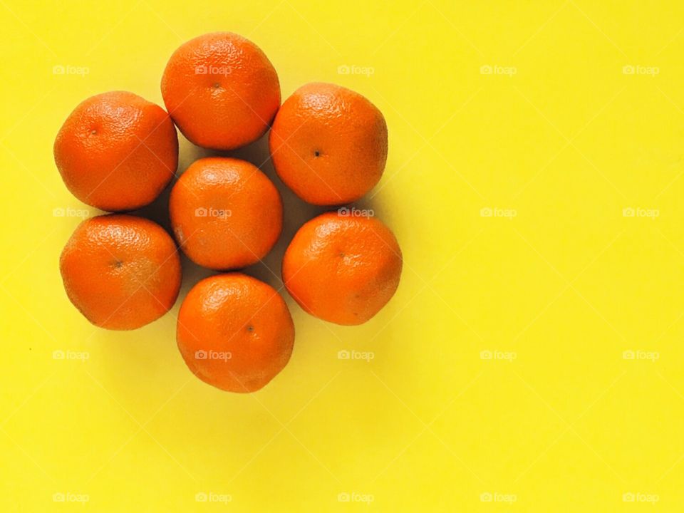 Oranges in a round circular pattern on a bright yellow background 