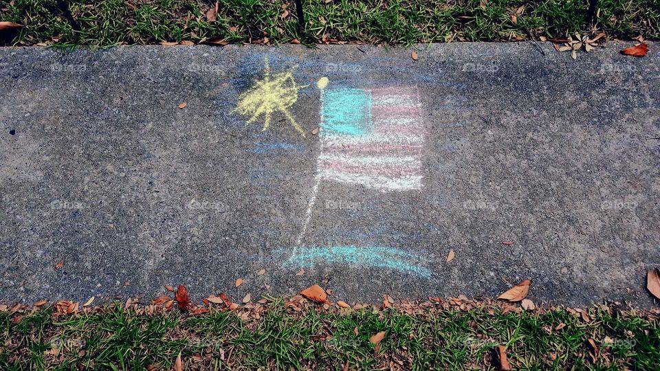 chalk art of American flag waving in the sunshine on concrete sidewalk