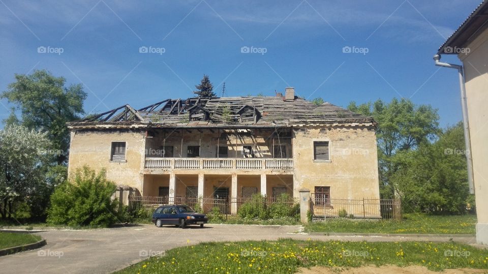 Destroyed old building with car on sunny day