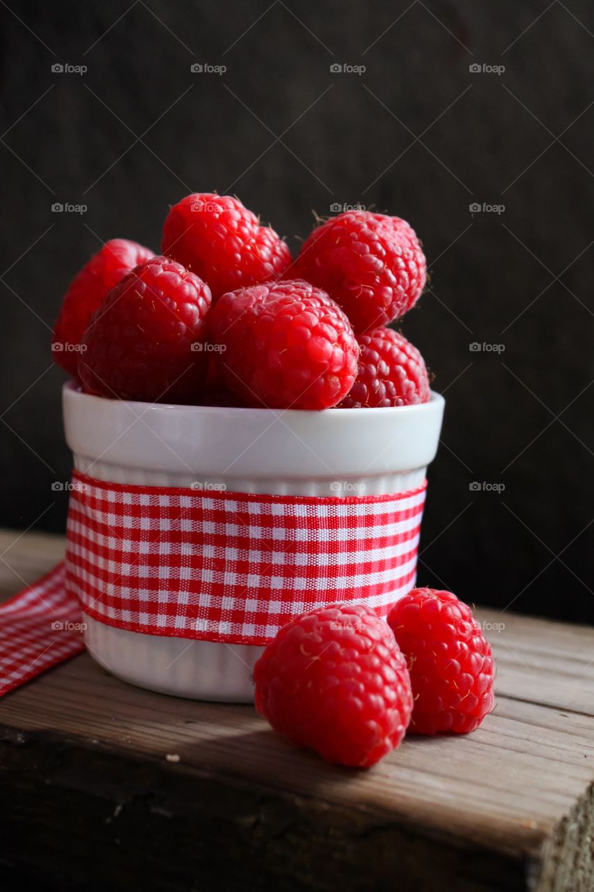 Raspberries in a bowl with gingham ribbon