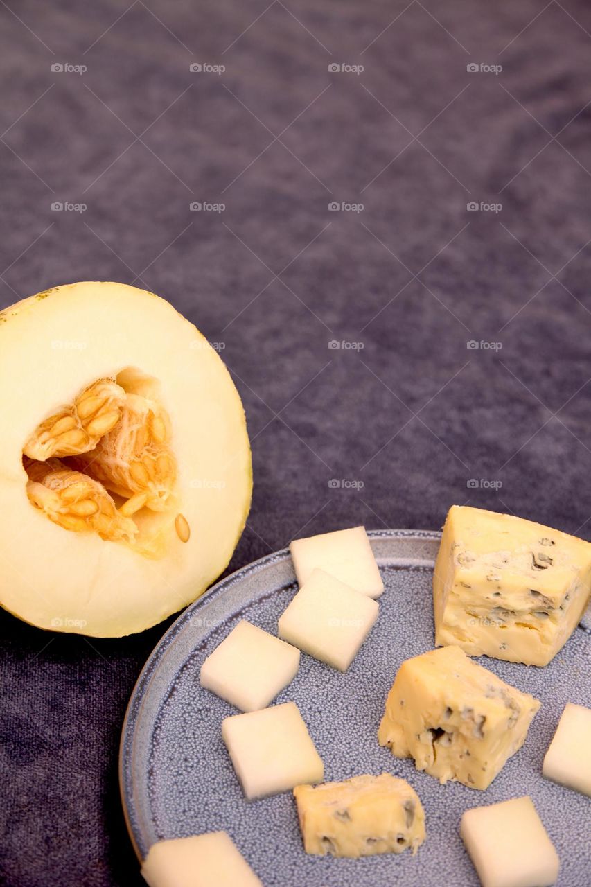 Melon with blue cheese on a blue plate.