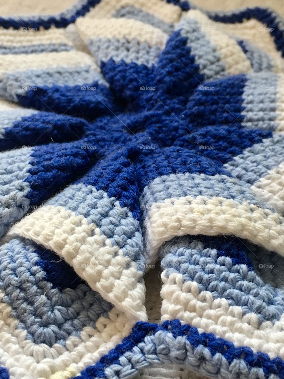 Symmetrical hand crochet/knit potholder in shades of blue closeup 