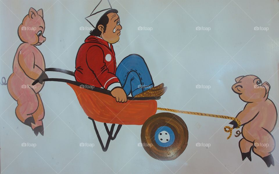 Colorful wall art (two pigs pushing and pulling a cheap in a wheel barrel) in a local small neighborhood family restaurant which caters to Mexicans in San Miguel de Allende, Mexico.