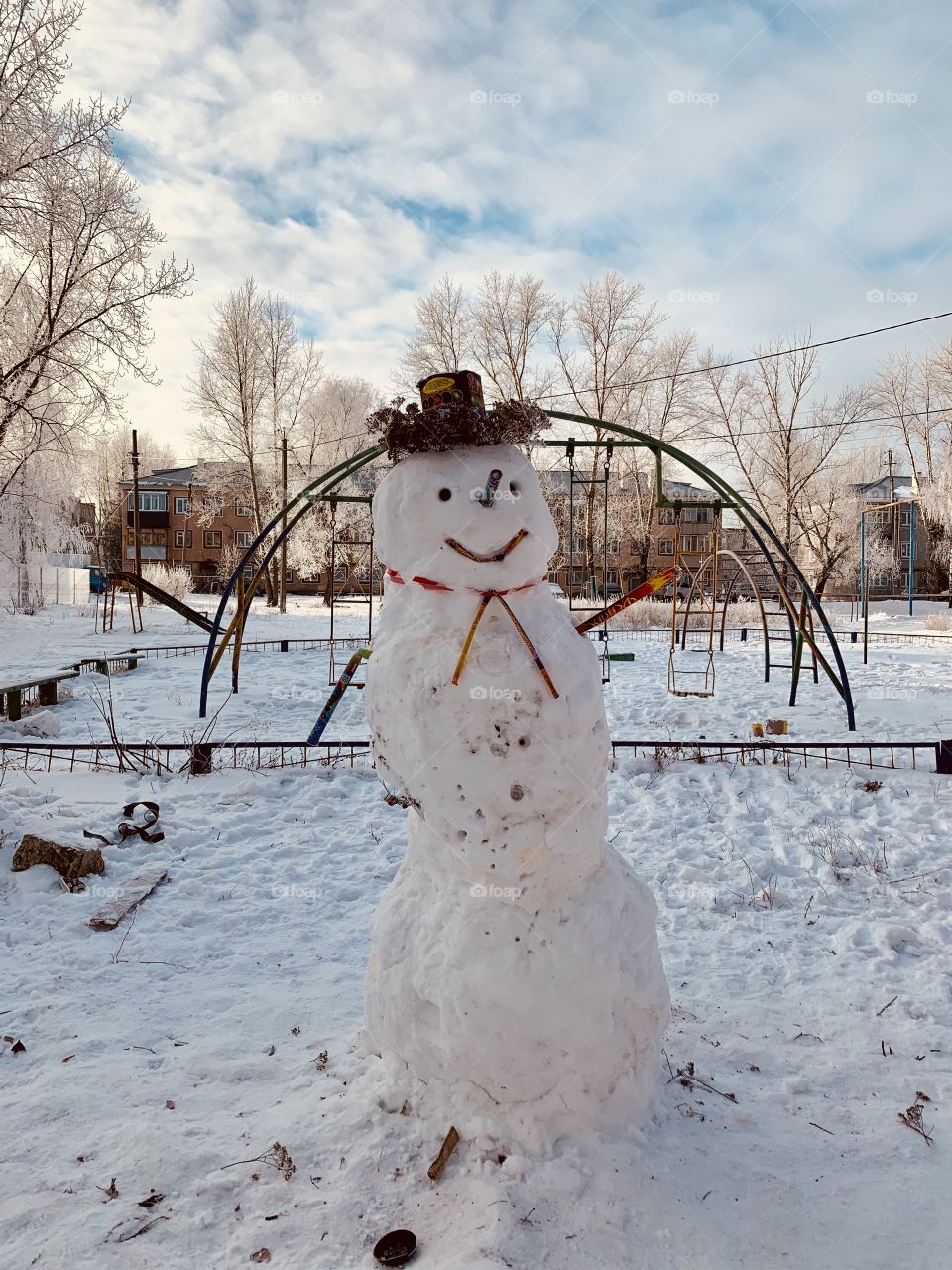 Big snowman in a hat on a winter playground in the courtyard of the house