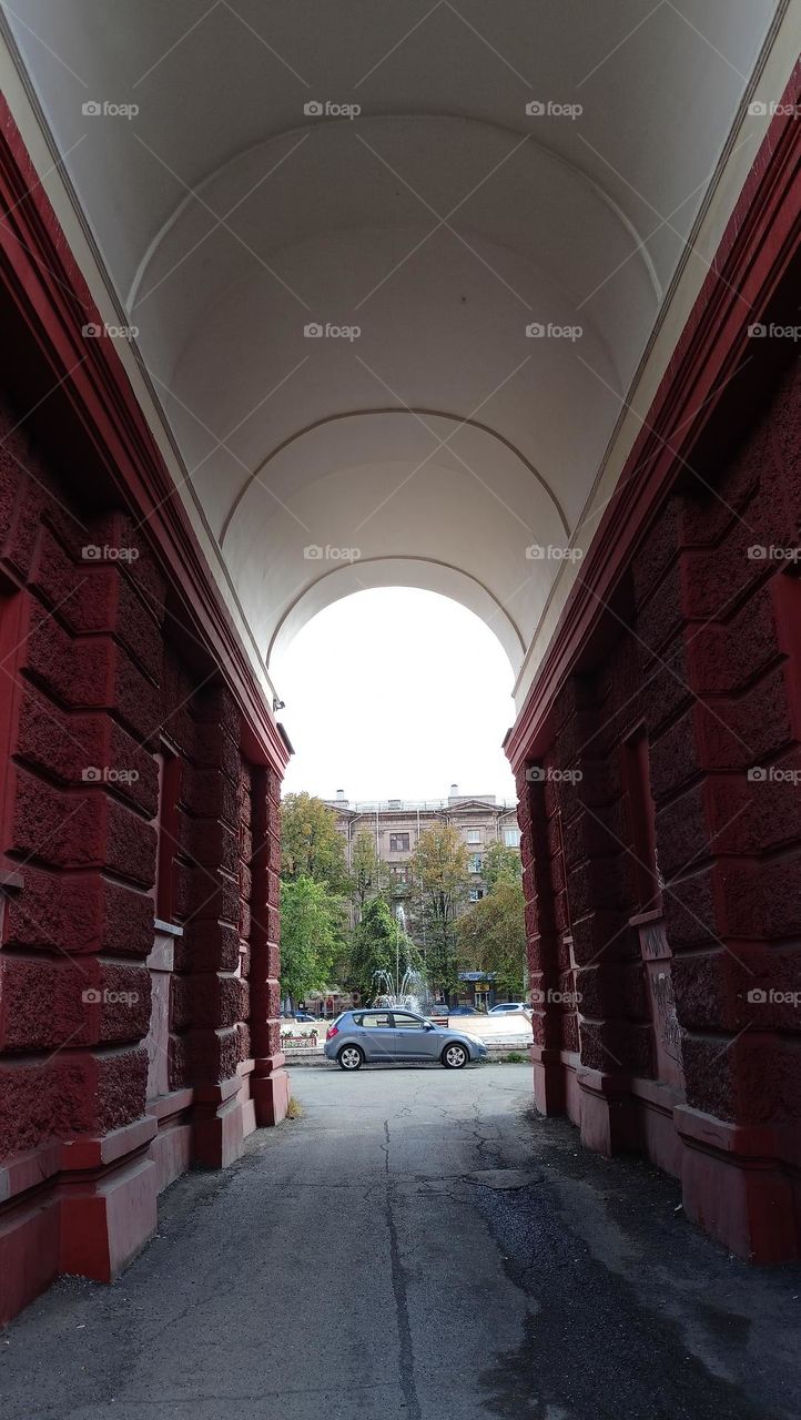 View through the arch, cityscape, arch, car, square,fountain, September in the city, sunny day