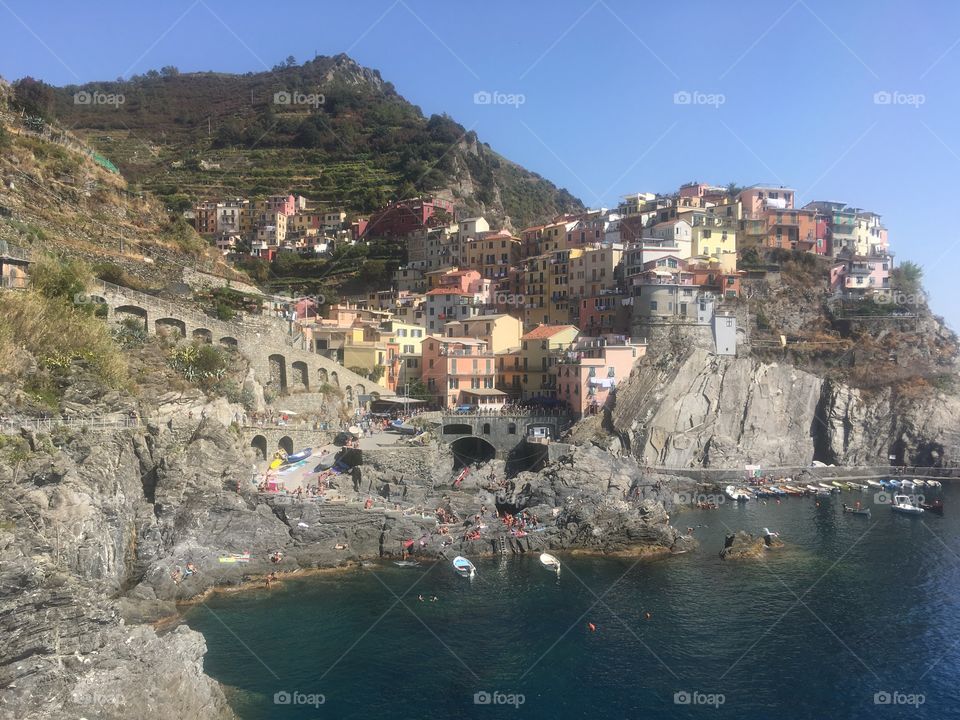 View of the coastal cliff side town of Manarola, in Liguria, Italy. Part of the Cinque Terre UNESCO World Heritage Site. Known for its pretty hillside properties overlooking the Mediterranean Sea. Seen in Summer.