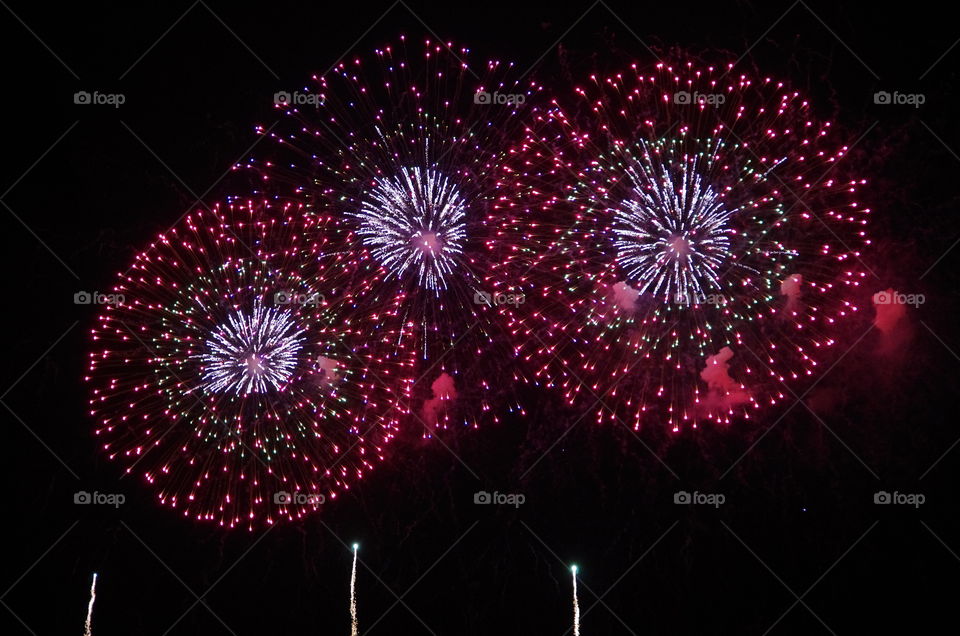 Exterior, night.  Honolulu, Hawaii, USA.  Fireworks spray the night with colourful bursts.