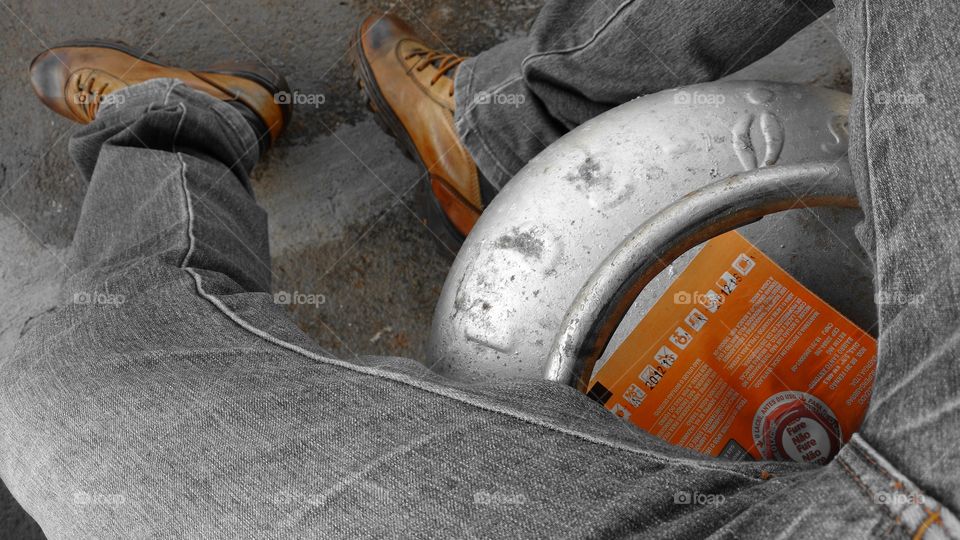 Sentado em um botijão de gás.