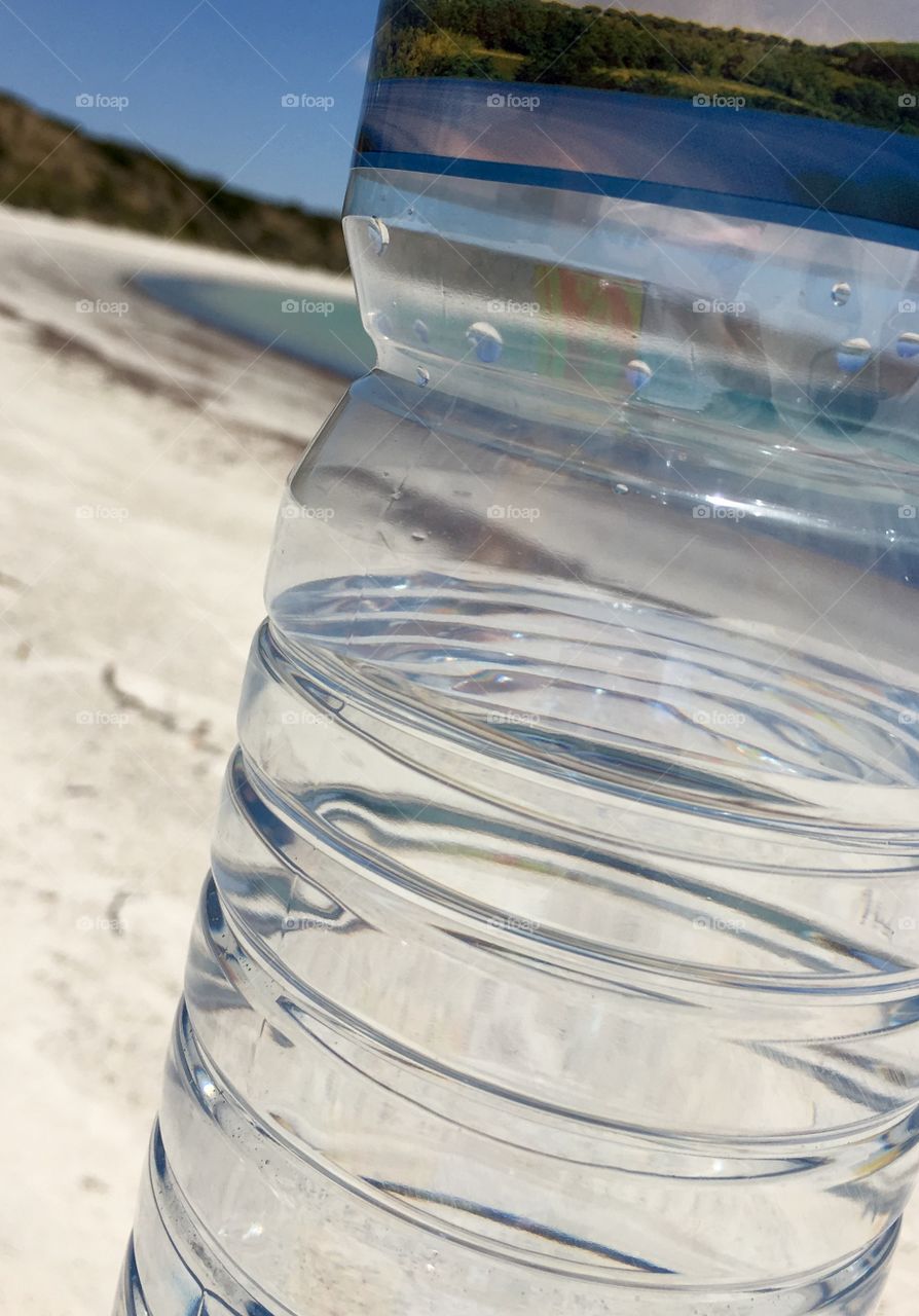 Ocean and ocean horizon seen through a clear glass bottle of spring water 