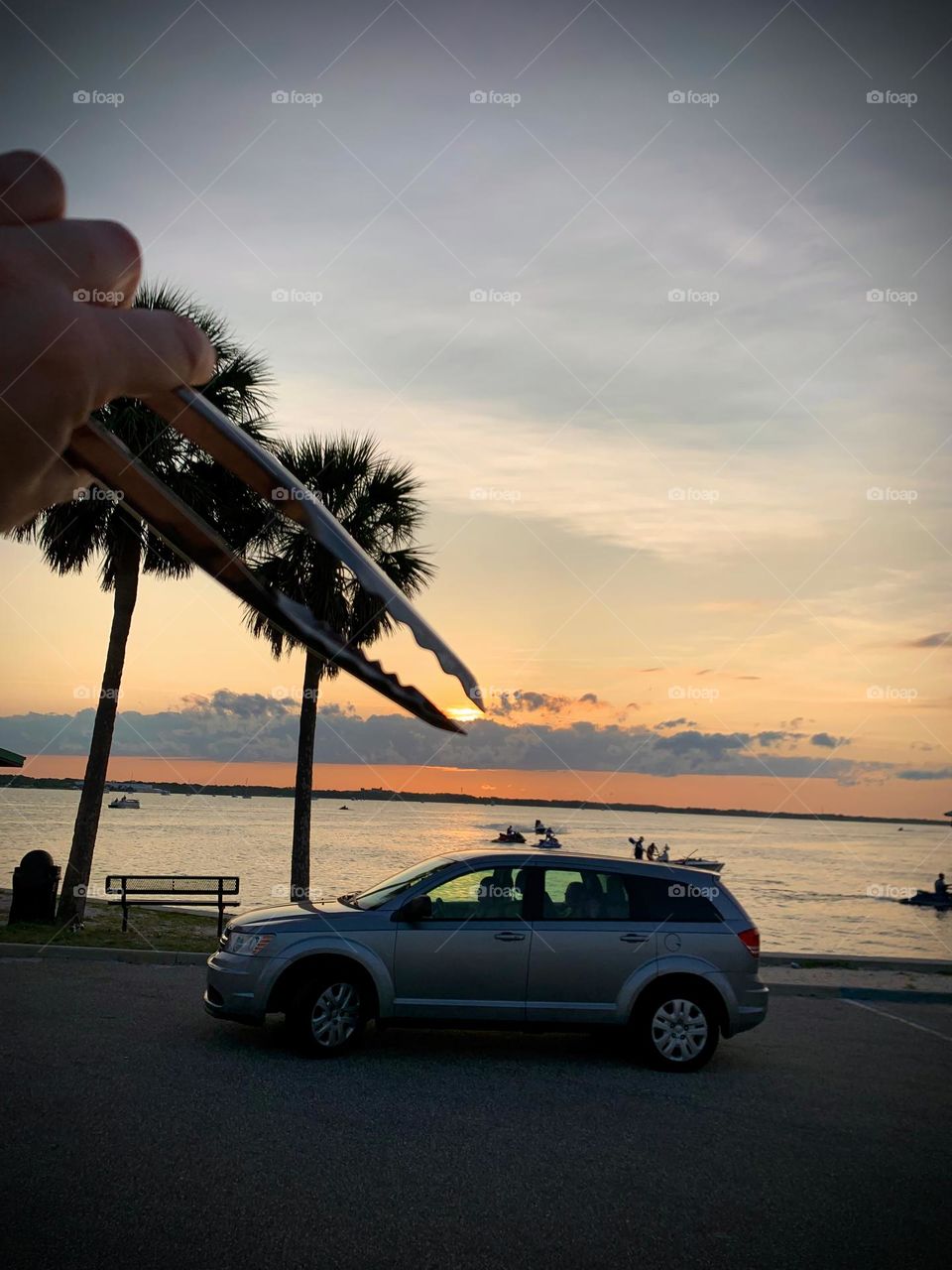 Sun From Sunset Seems To Be Grabbed By The BBQ Tongs From Above On Top Of A Vehicle At The Seashore On A Tropical Environment.