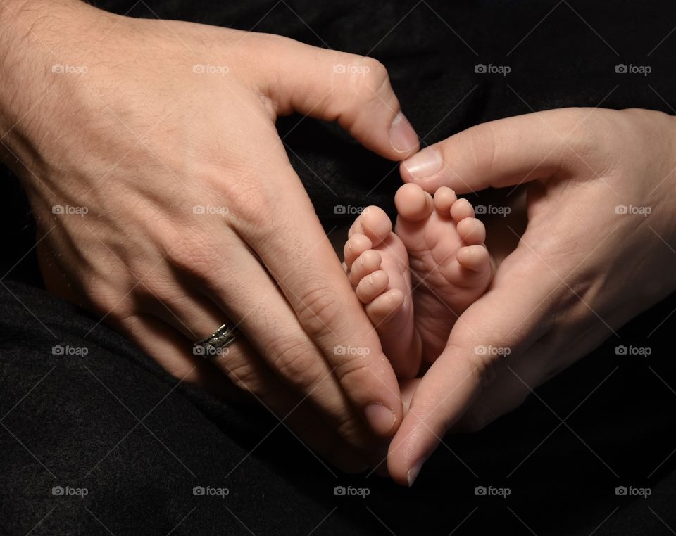 Mother and father’s hands holding infant’s tiny feet