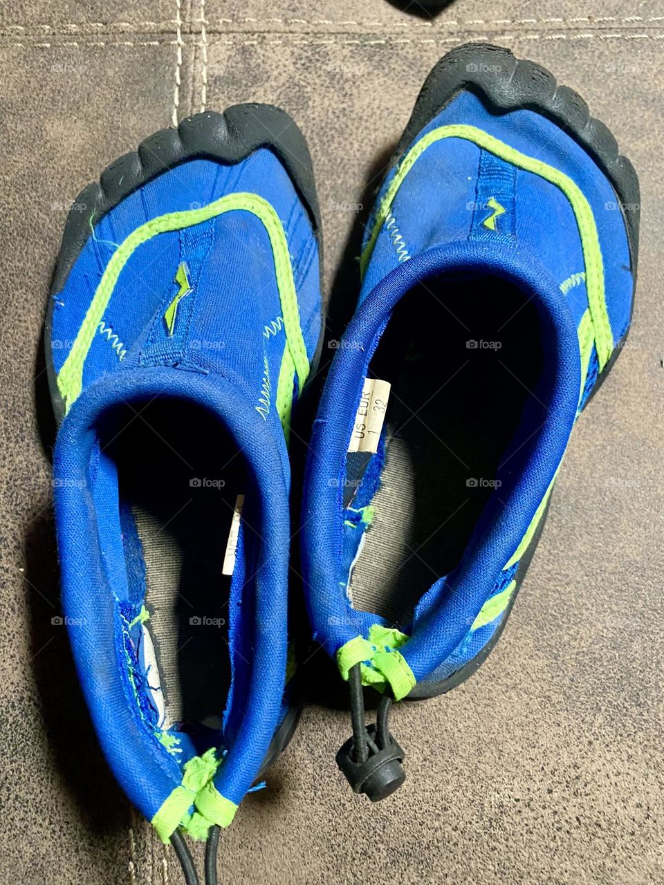 A pair of children’s black, blue, and green water shoes with a drawstring. 