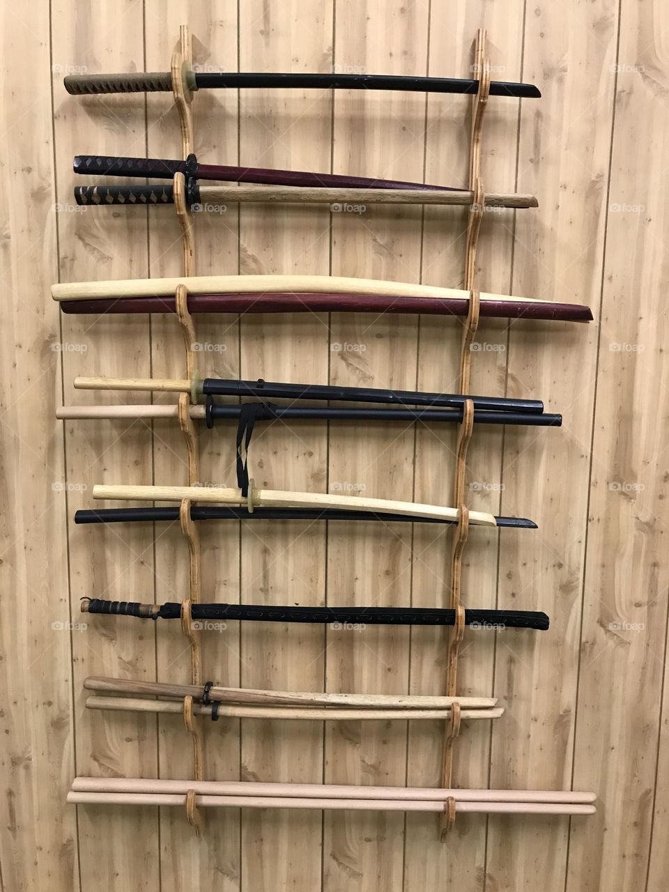 An array of training weapons organized on a mounted rack at the Japanese martial arts dojo.