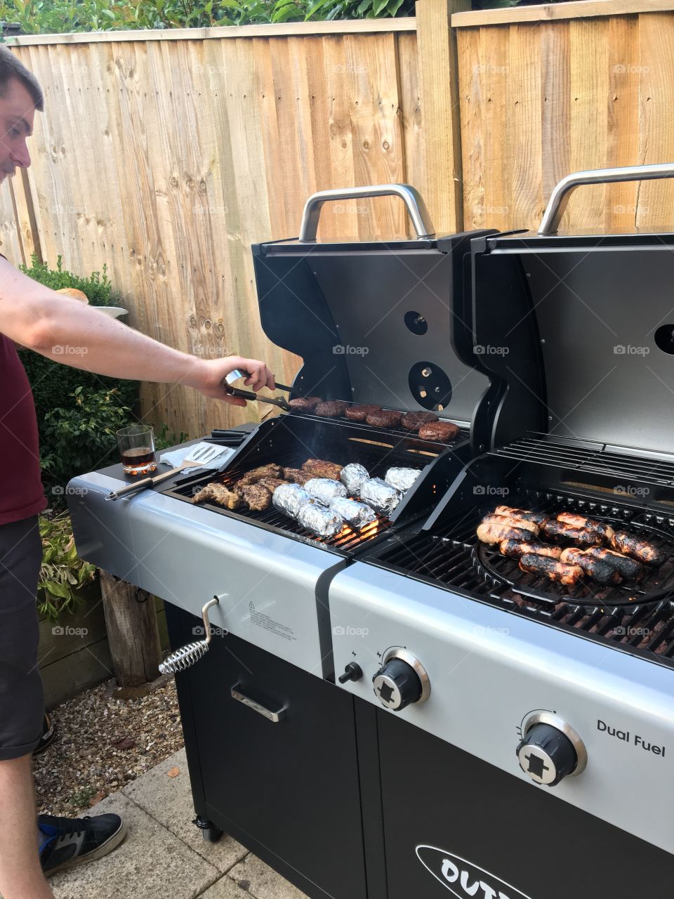 A man turns meat on a large barbecue or bbq