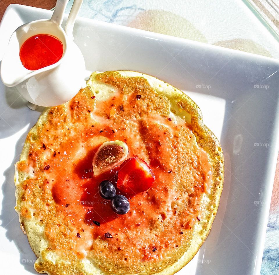 Pancakes topped with fresh fruit and strawberry sauce 