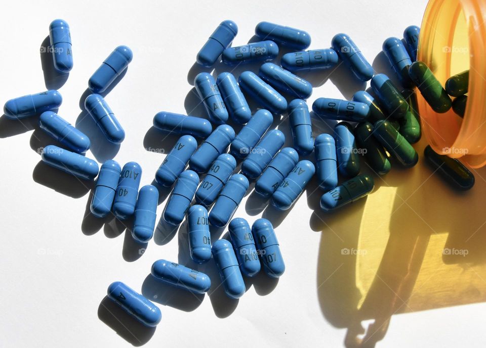 Blue pills spilling out of a bottle 