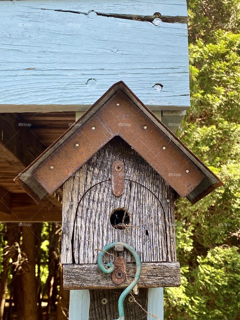 A wooden birdhouse hanging from the side of a wooden building