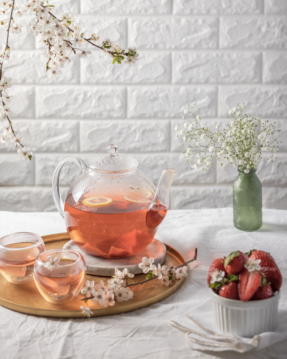 Glass tea pot with fruit tea and spring flowers 