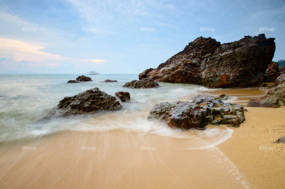 Sea waves lash line impact rock on the beach.