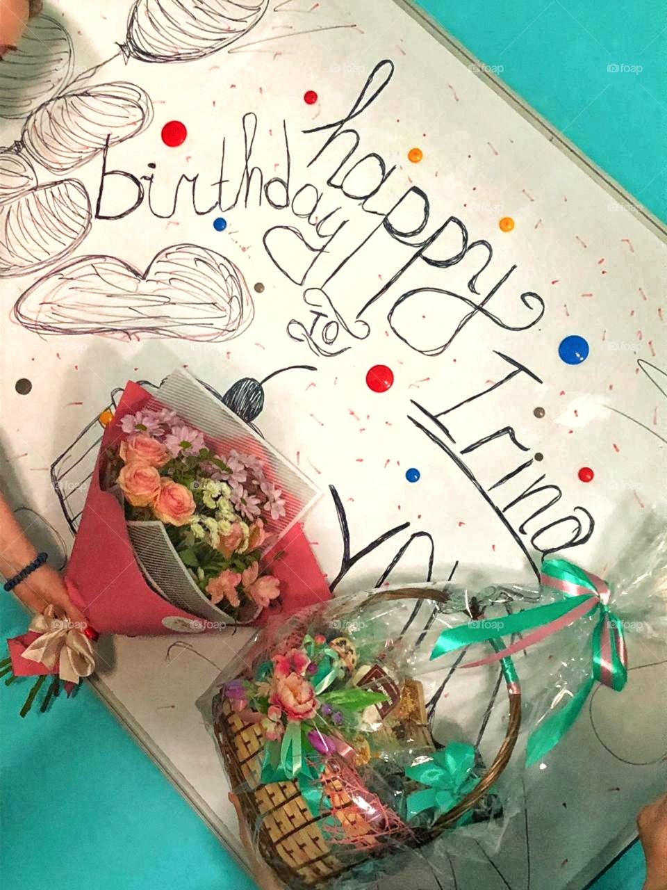 поздравления именника по имени Ирина в день рождения, букет цветов и подарок на фоне поздравления на доске