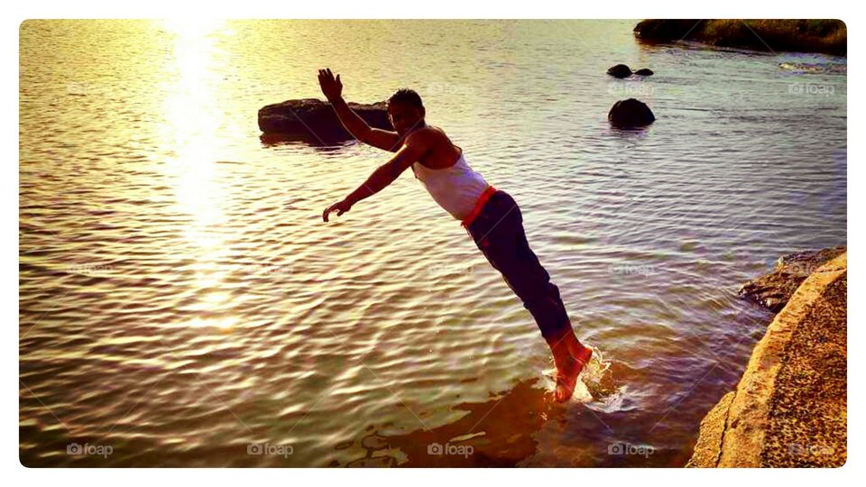 Man diving in sea during sunset