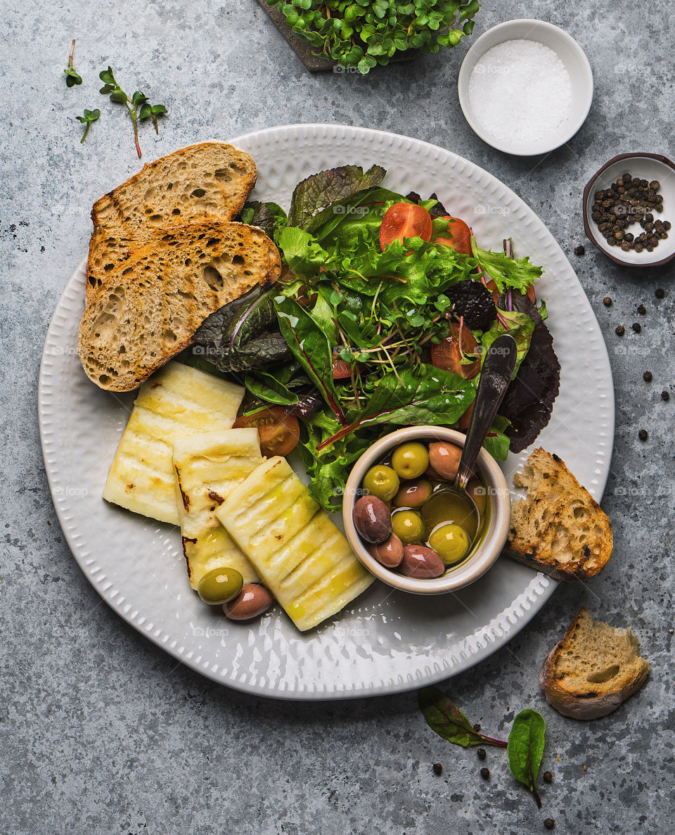 Plate with grilled cheese, salad and olives