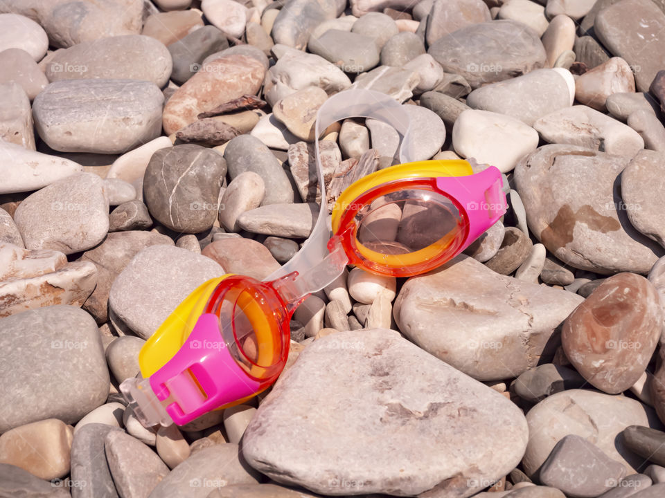 Goggles for swimming and diving lie on the rocky beach of the southern coast of the sea