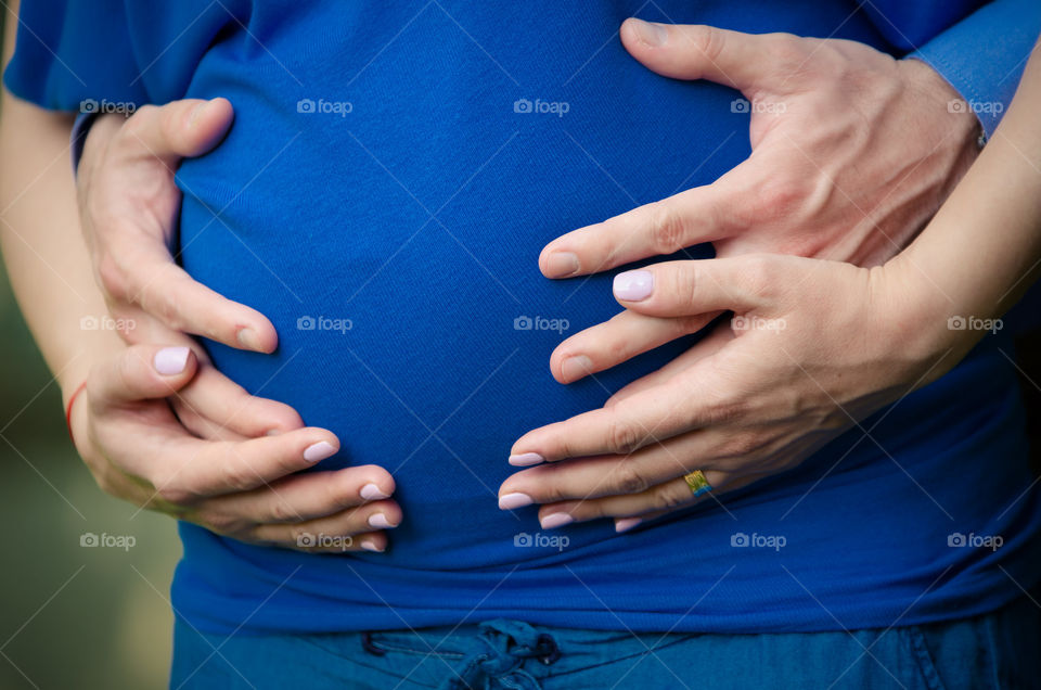 Close-up of human hands holding pregnant belly