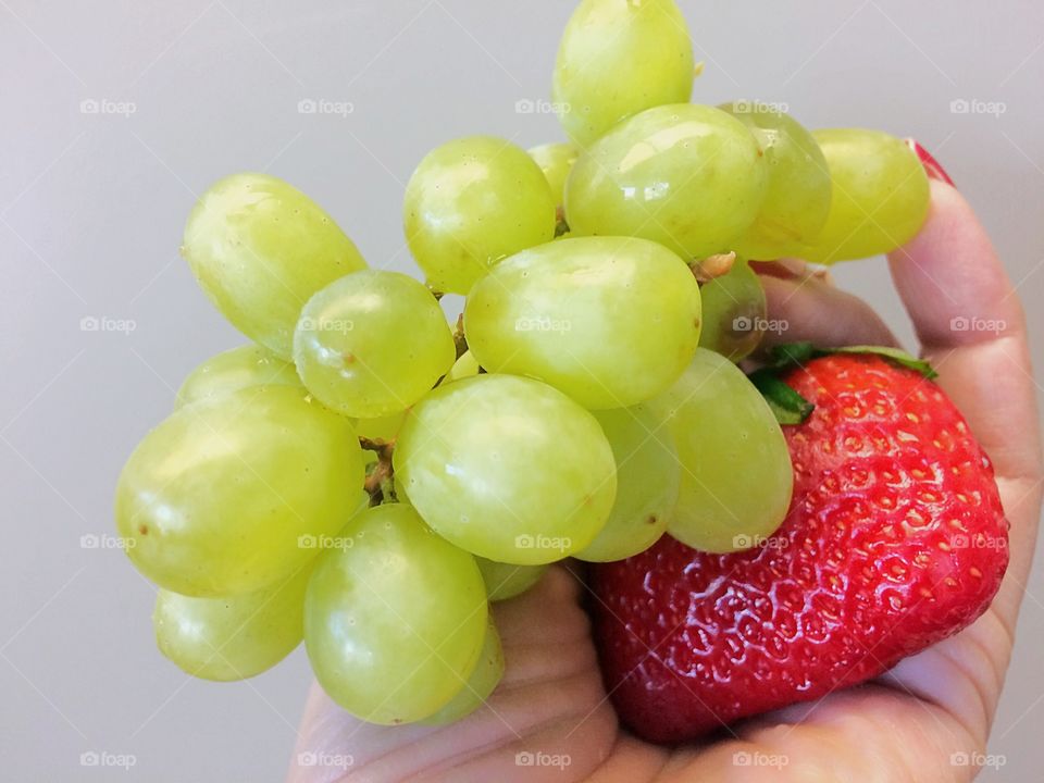 Woman hand holding grapes and strawberry