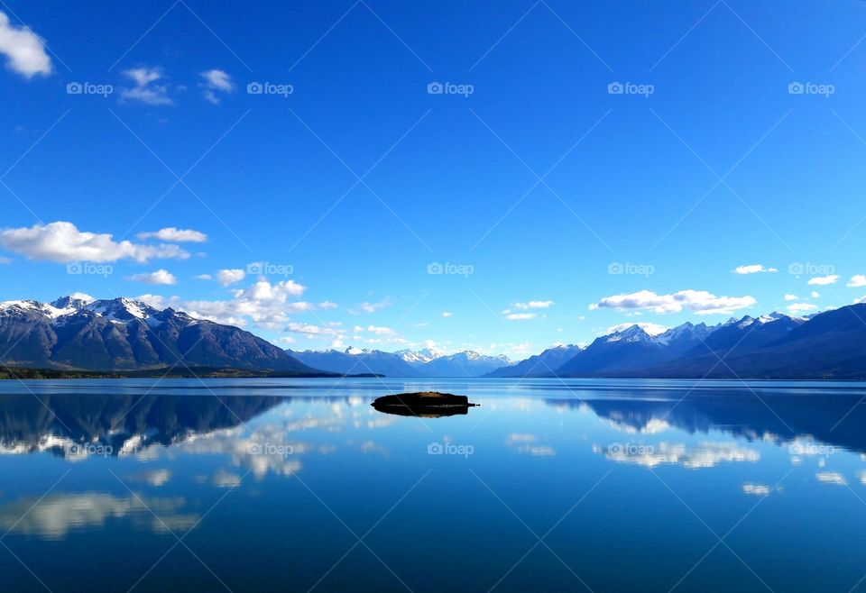 Snowy mountains reflecting in sea