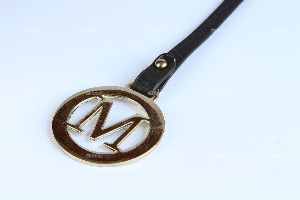 Letter M from metal logo and leather strip isolated macro shot