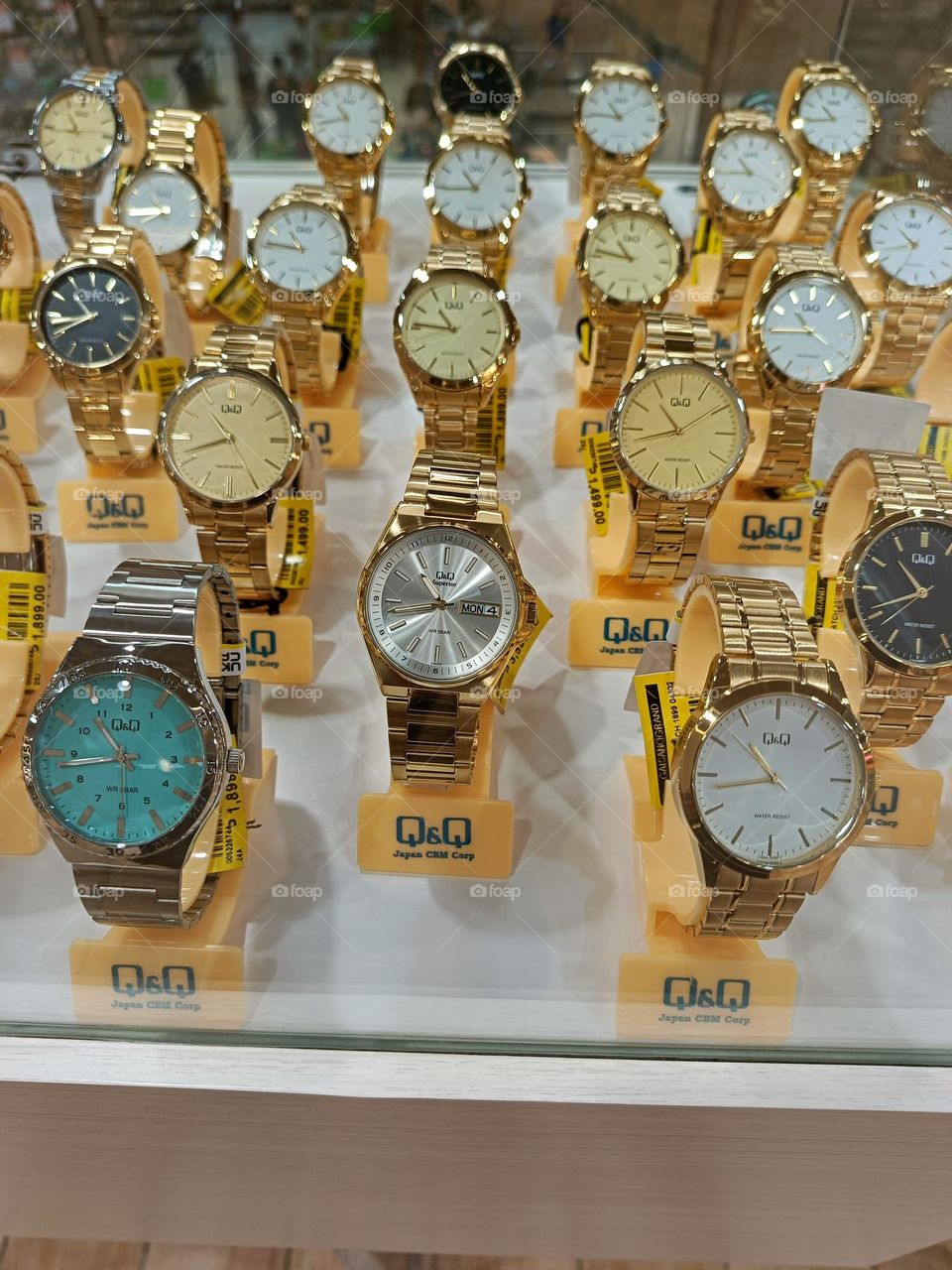 A display of Q&Q watches in various colors and gold tones.