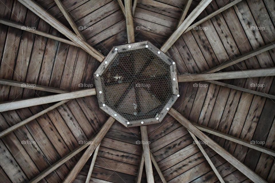 The ceiling of a gazebo presents with an all wooden architecture and unique design.