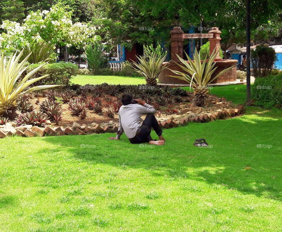 enjoy relaxing on greens grass lawn without shoes and making a mobile call