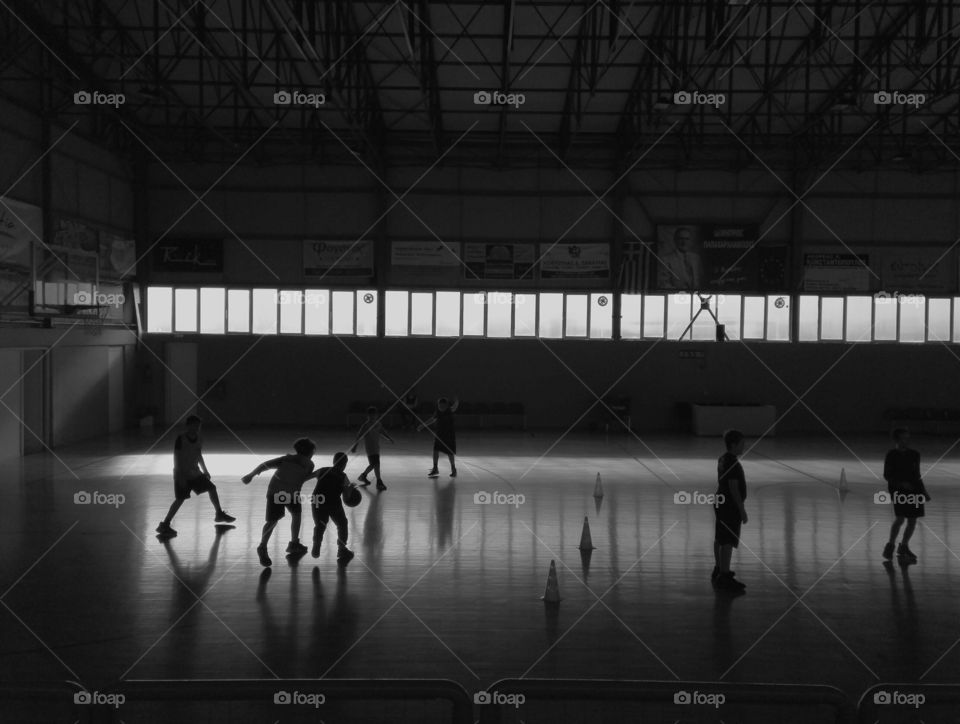 school kids playing basketball inside hall black and white