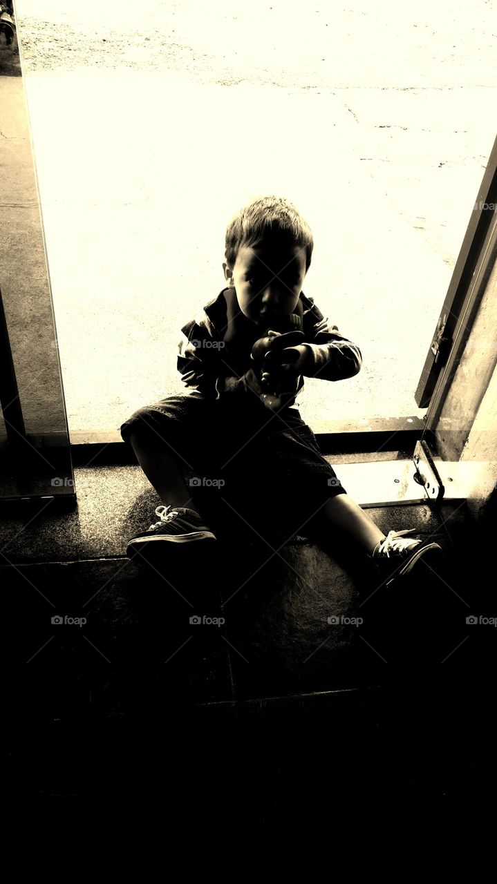 Criança com brinquedo, sentado ao chão.