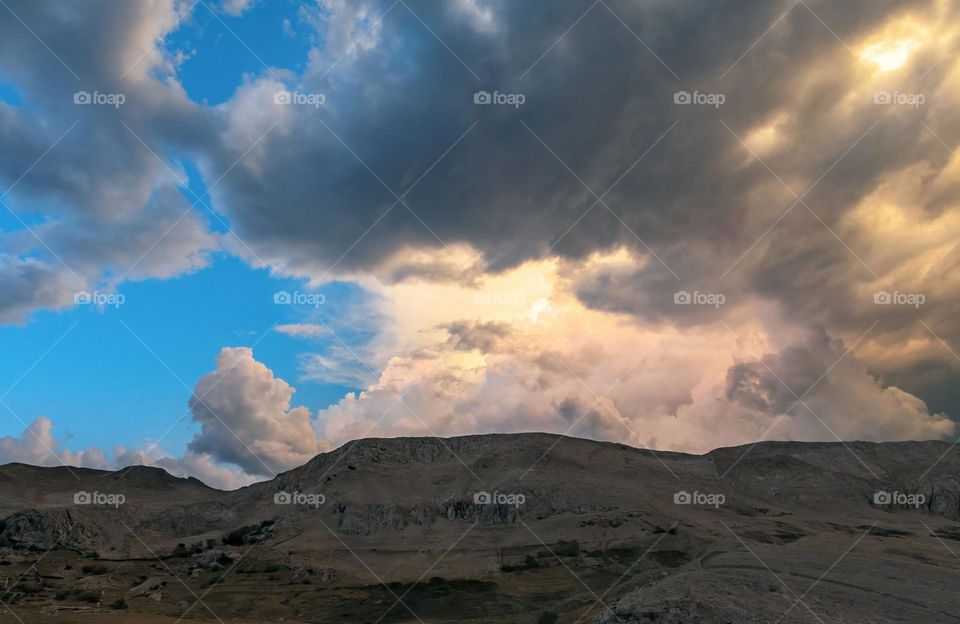 Dramatic stormy clouds above ridge on arid landscape