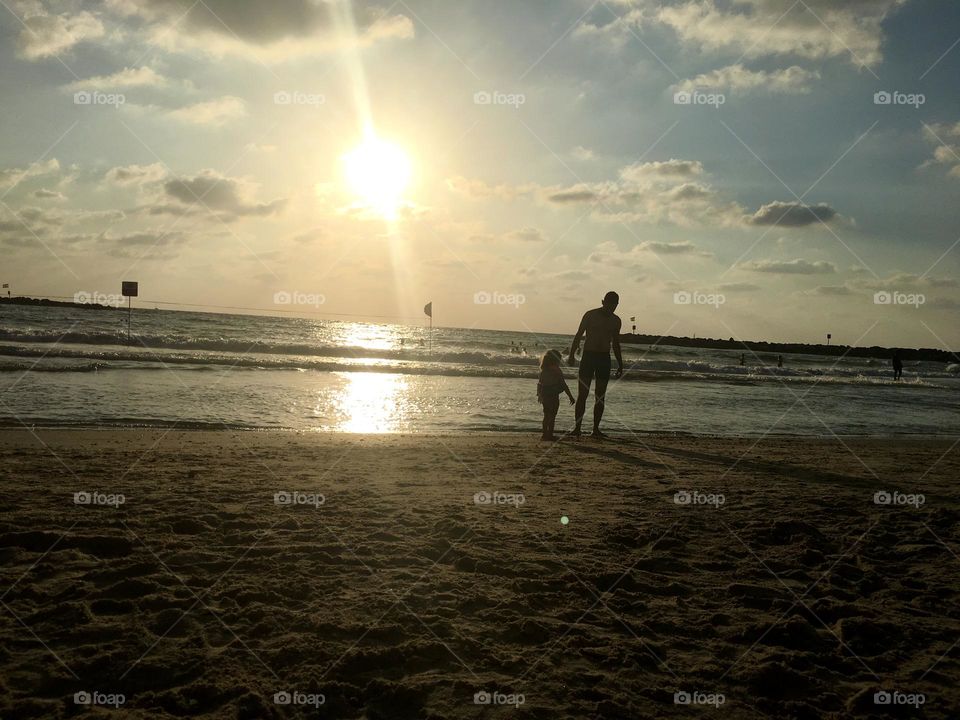 Man and a girl on sea line at sunset 