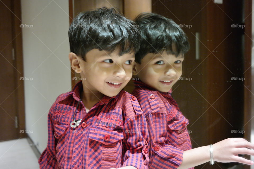 Happy cute boy looking at his reflection on mirror