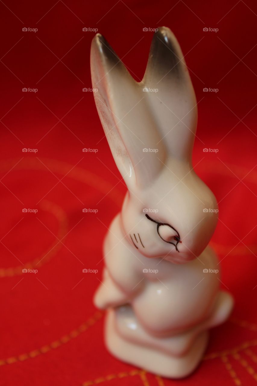 Miniature porcelain white bunny on a red background