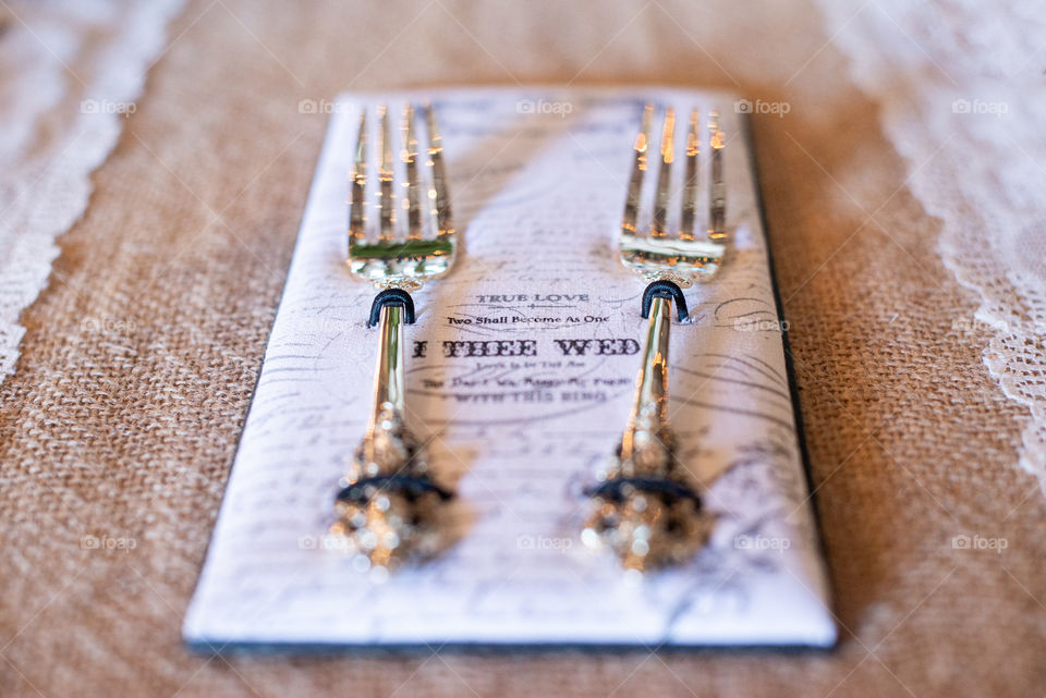 Two gold forks on text napkins on canvass table