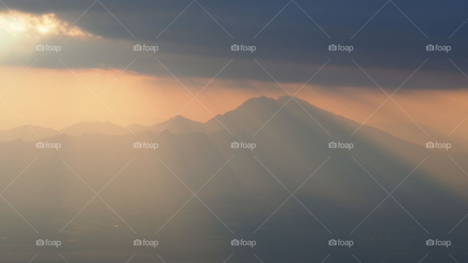 Eerie sunrays down mountain. Unusual rays coming down clouds mountain epic landscape postcard