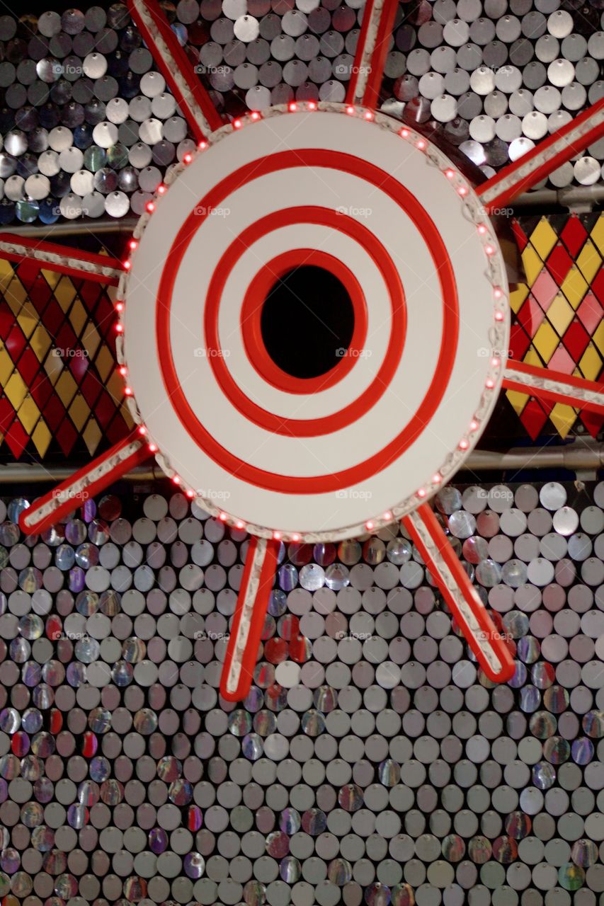 Lighted target with shiny background of metal discs and red and yellow diamond-shaped metal pieces