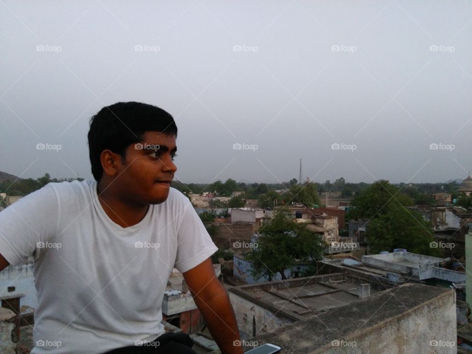 Teenage boy sitting on top of building