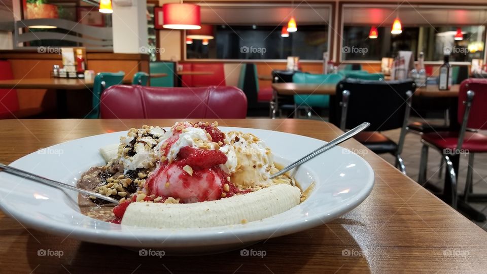 A banana split on a table in a local diner.