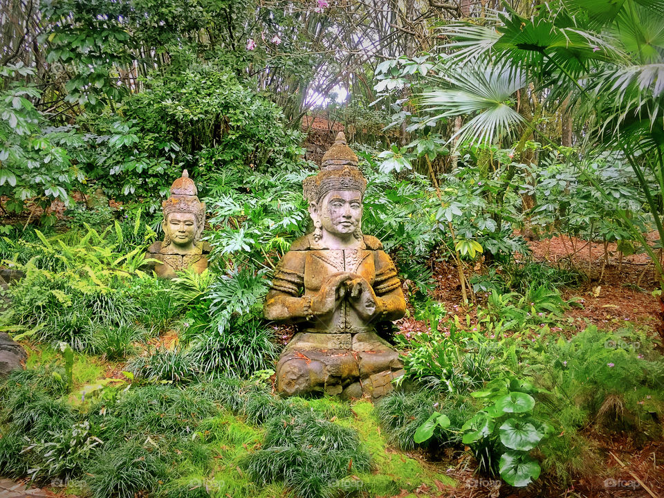 Time for relaxation. Green garden with statues in Asian style. 