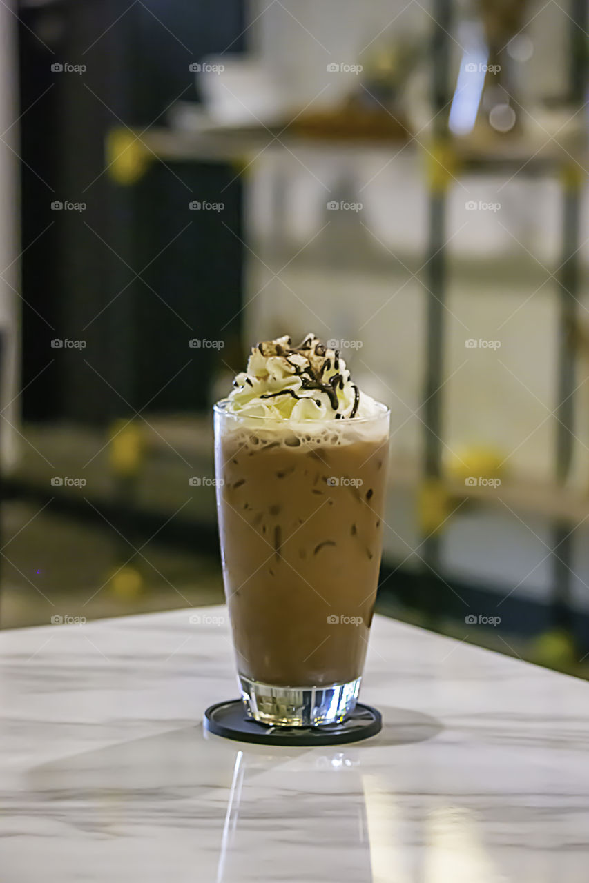 Iced cocoa put whipped cream in a glass on the table.