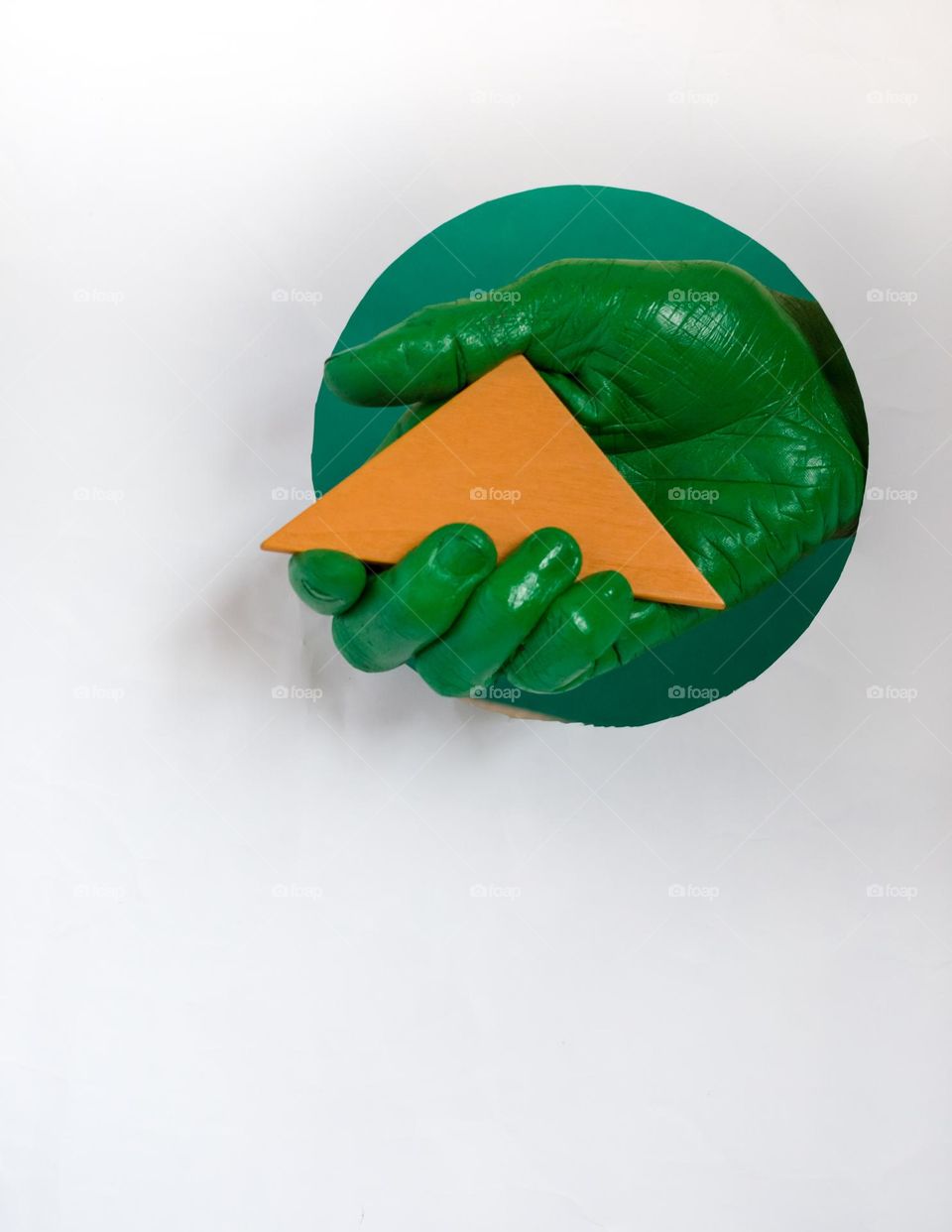 Orange color triangle in green painted hand.