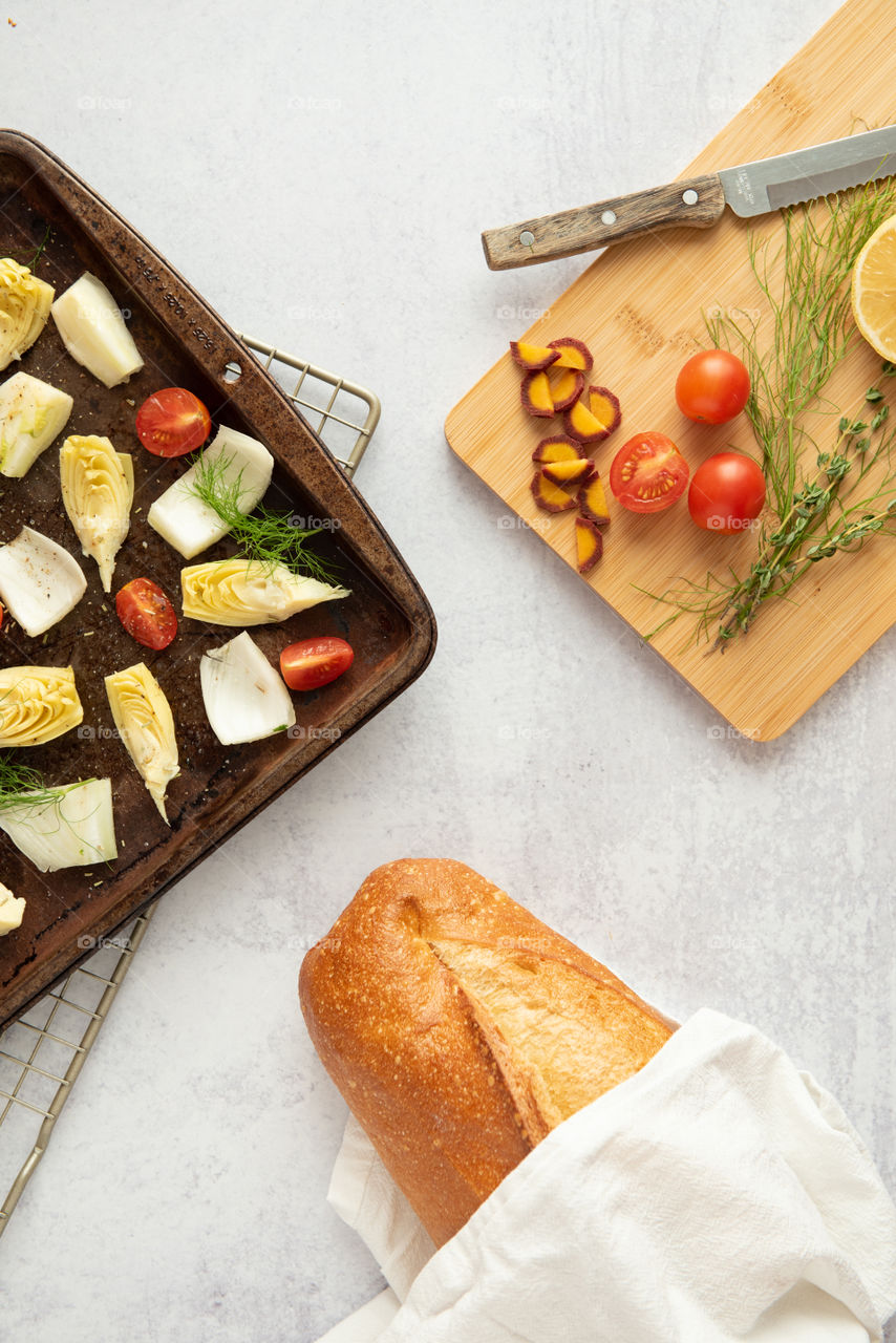 Flat lay of a sheet pan of vegetables and loaf of bread 