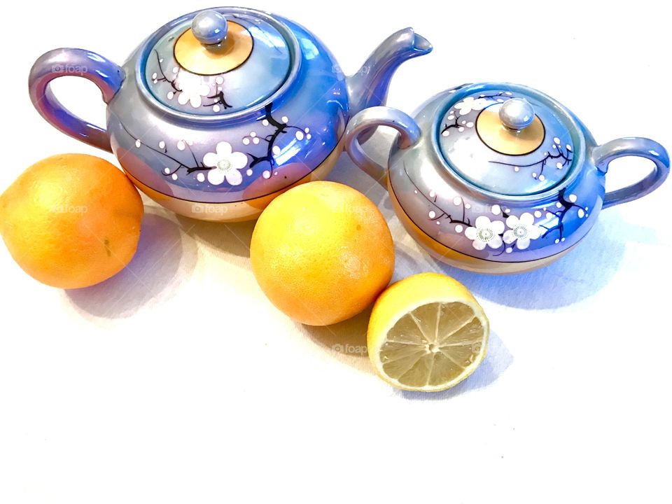 Still life of tea pots with oranges and lemon